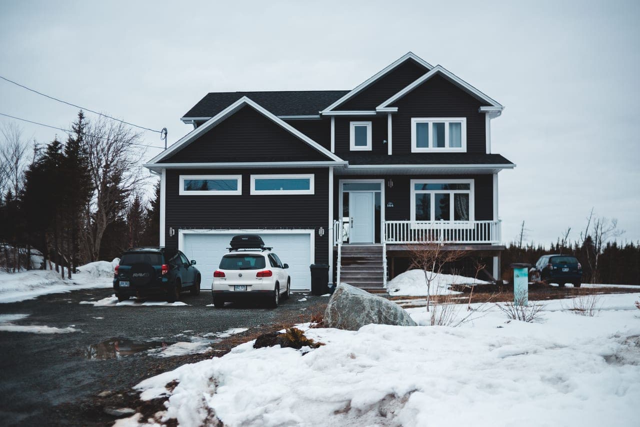 A short residential driveway cleared of snow in front of a garage