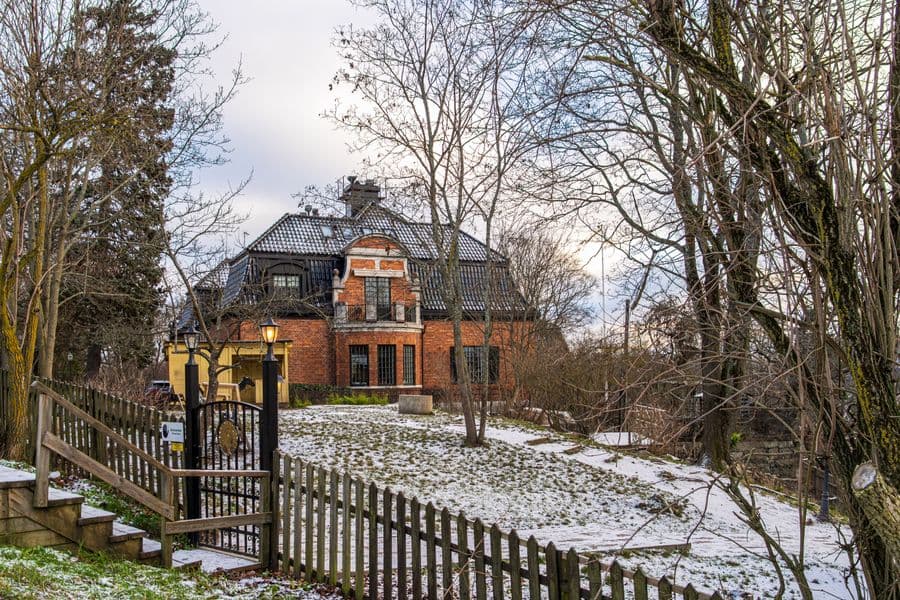 A red brick house behind a snow-covered garden in winter