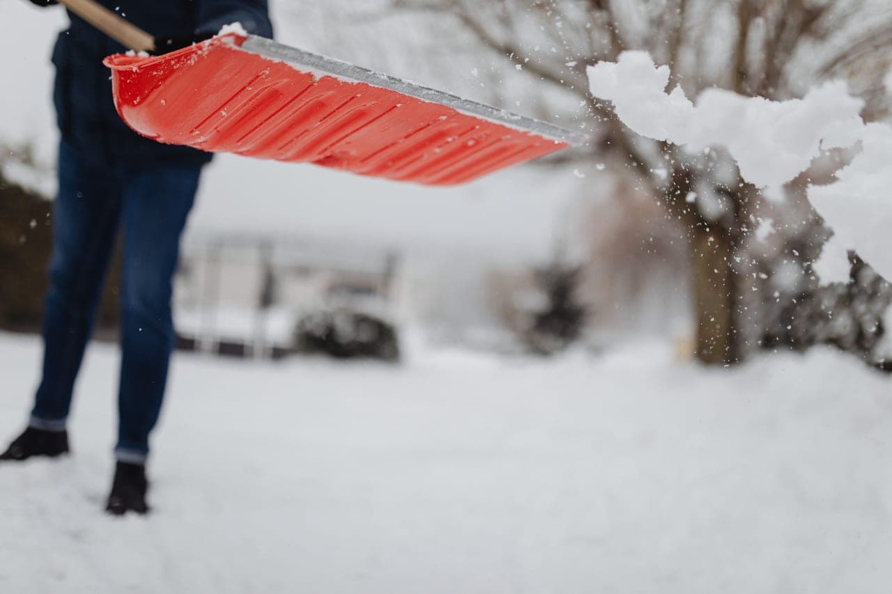 A person shoveling snow from a driveway with an upright posture