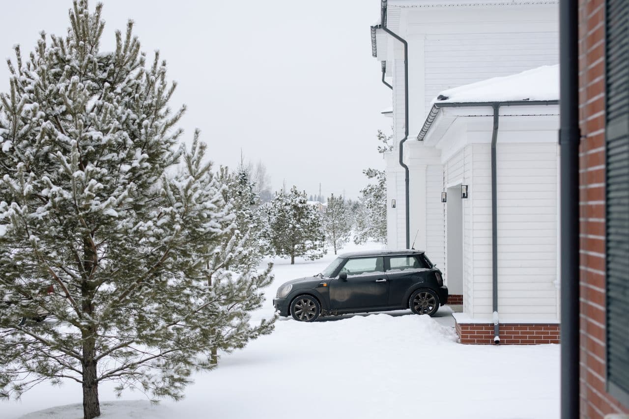 A car parked on a snow-covered driveway where the pavement edges are no longer visible