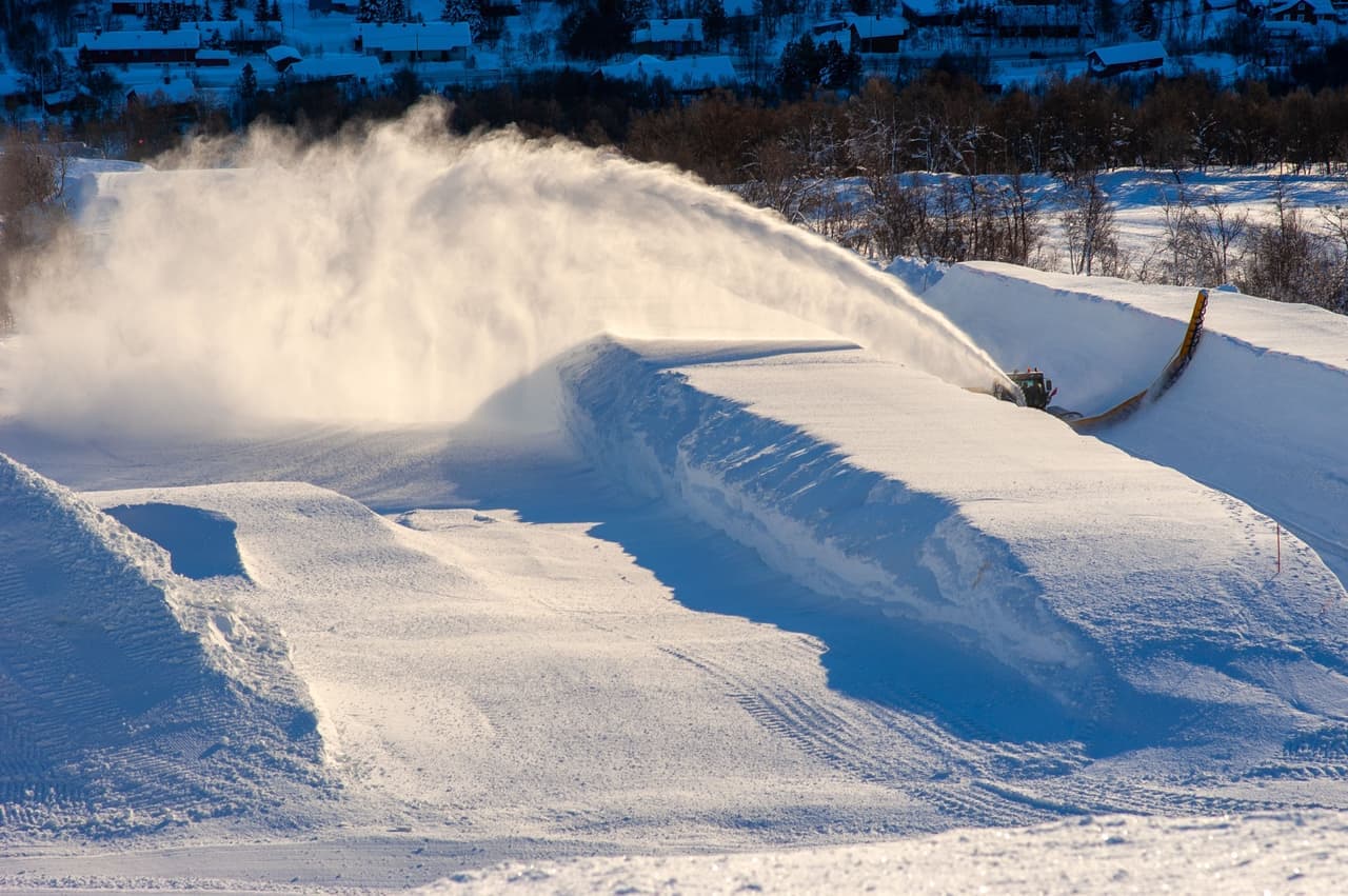 A snow blower on a gravel surface with light snow cover