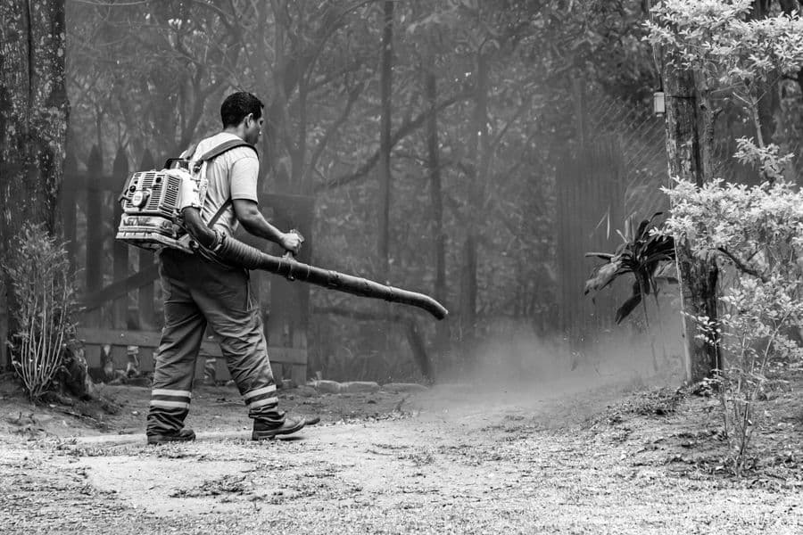 A person using a handheld blower along a path