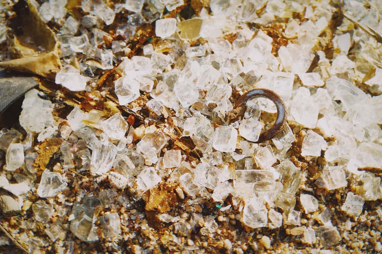 Coarse de-icer crystals scattered on an icy paved surface