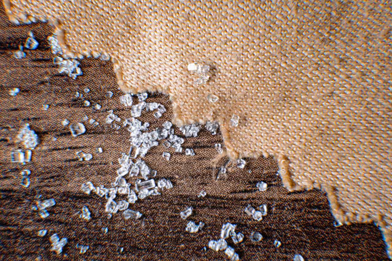 Ice melt pellets scattered on a concrete driveway with melted patches showing through