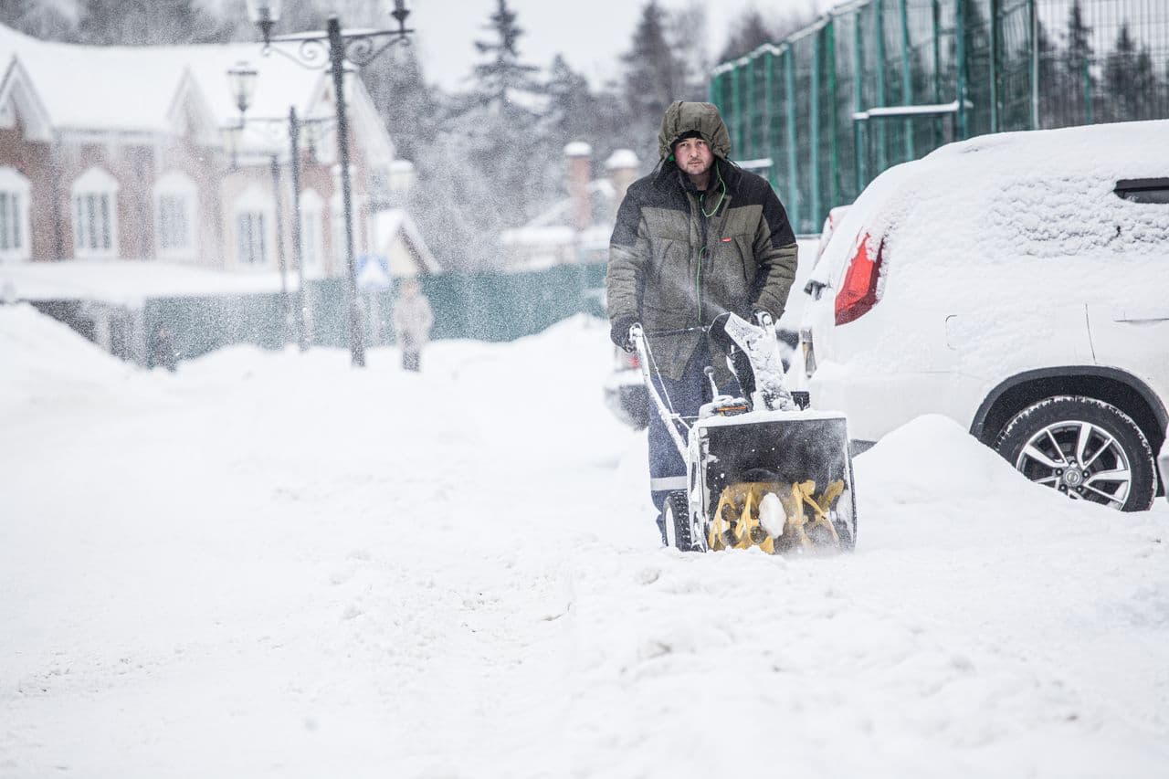 A snow blower clearing a driveway in winter