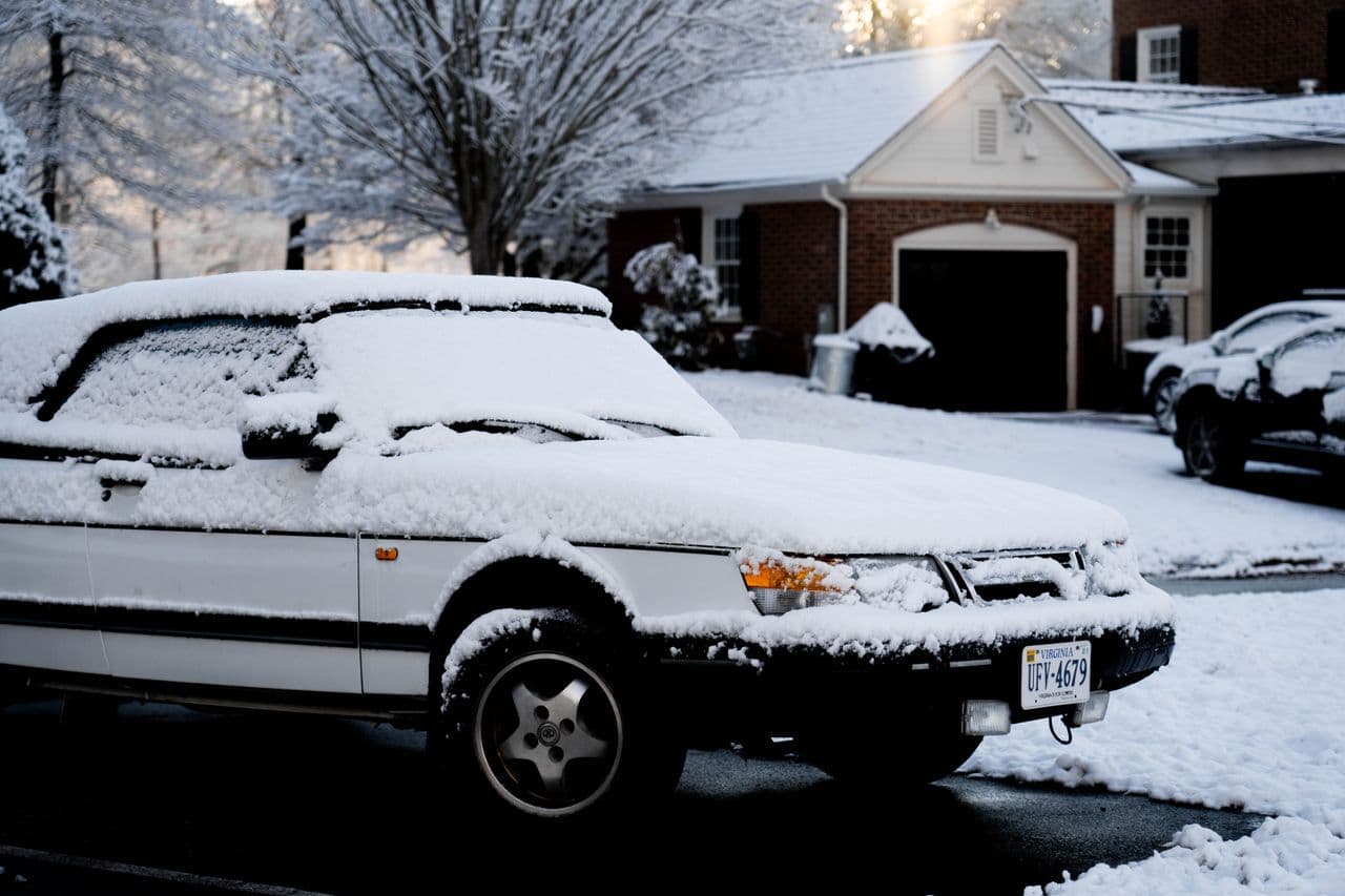A snow-covered suburban street and parked car after an overnight storm