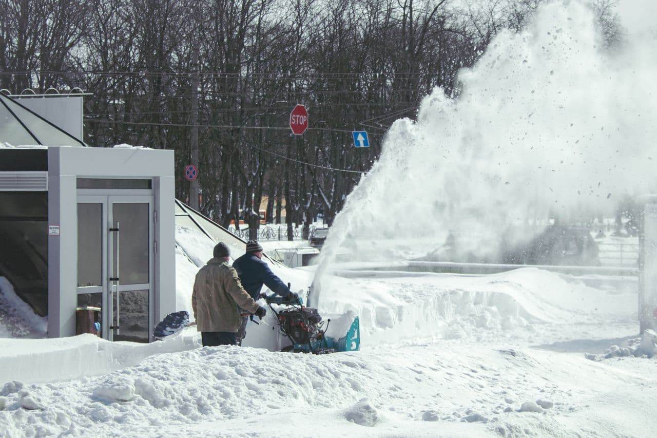 A single-stage snow blower clearing a paved driveway
