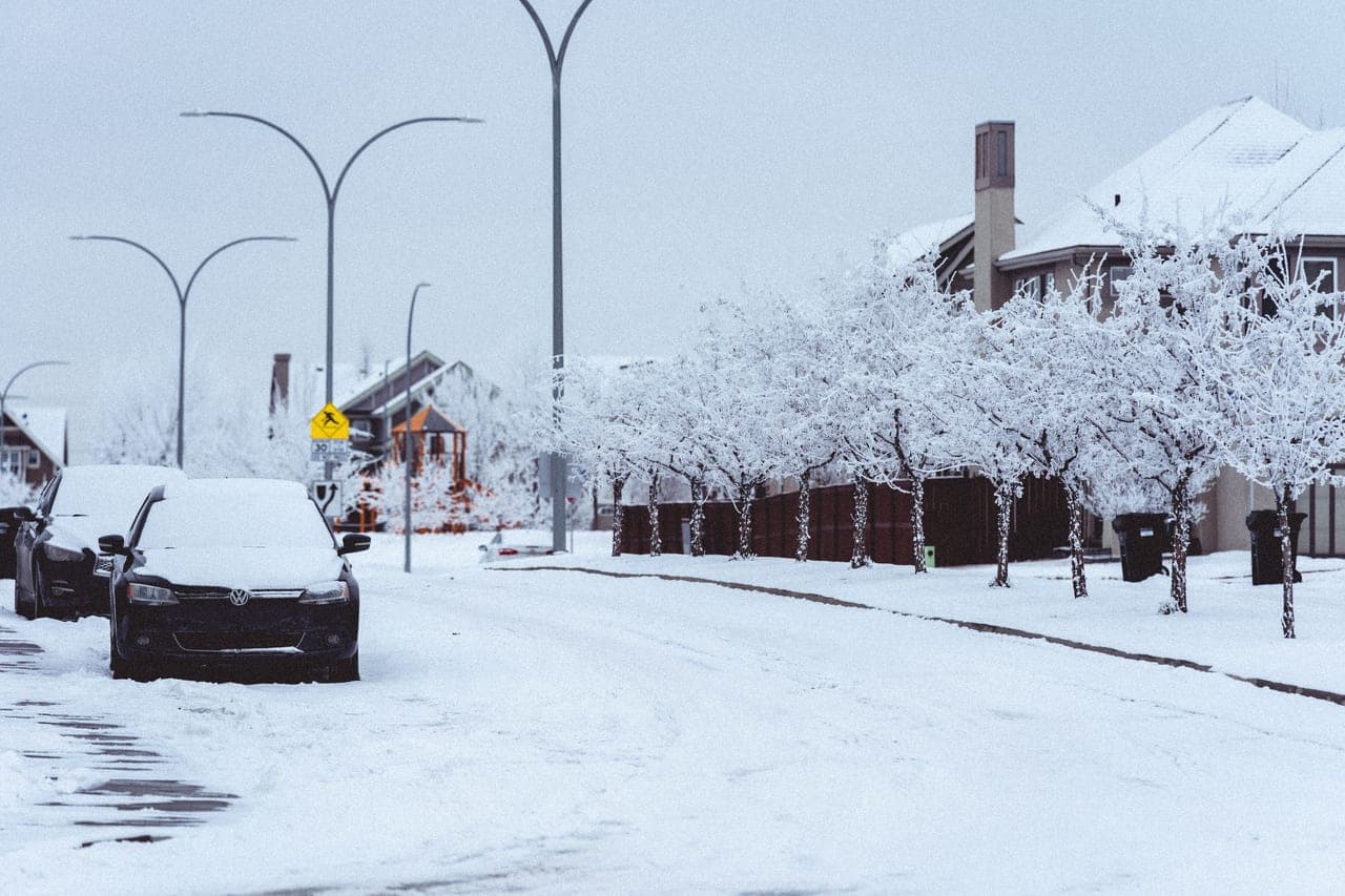 A parked car covered in fresh snow on a winter street