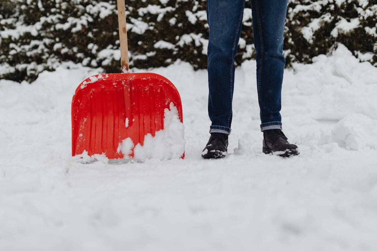 Heavy wet snow piled deep on a driveway with a shovel track cut through it