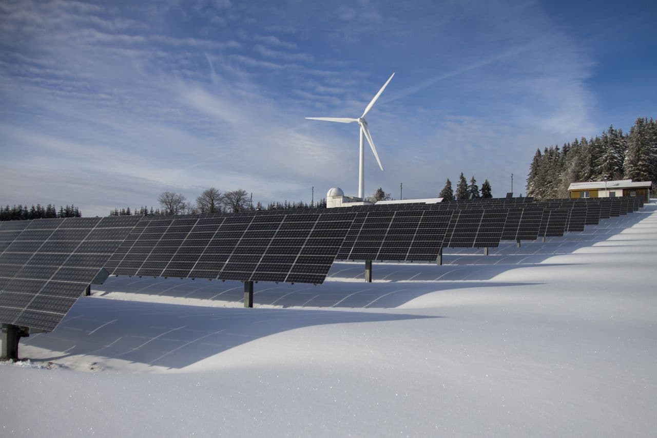 Solar panels and a wind turbine in a snow-covered landscape